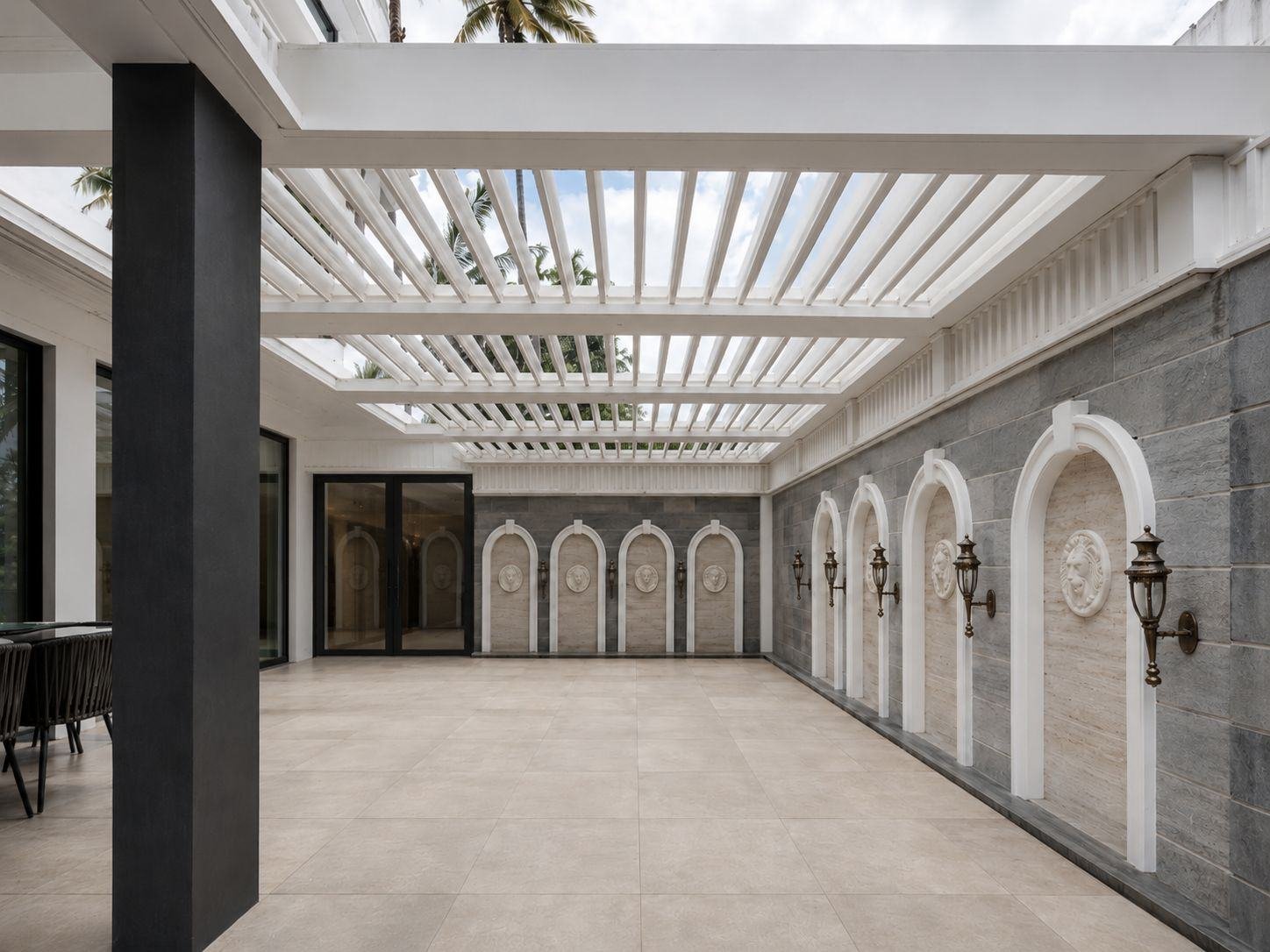 White louvre roof over a stone courtyard with arched wall niches and brass lanterns